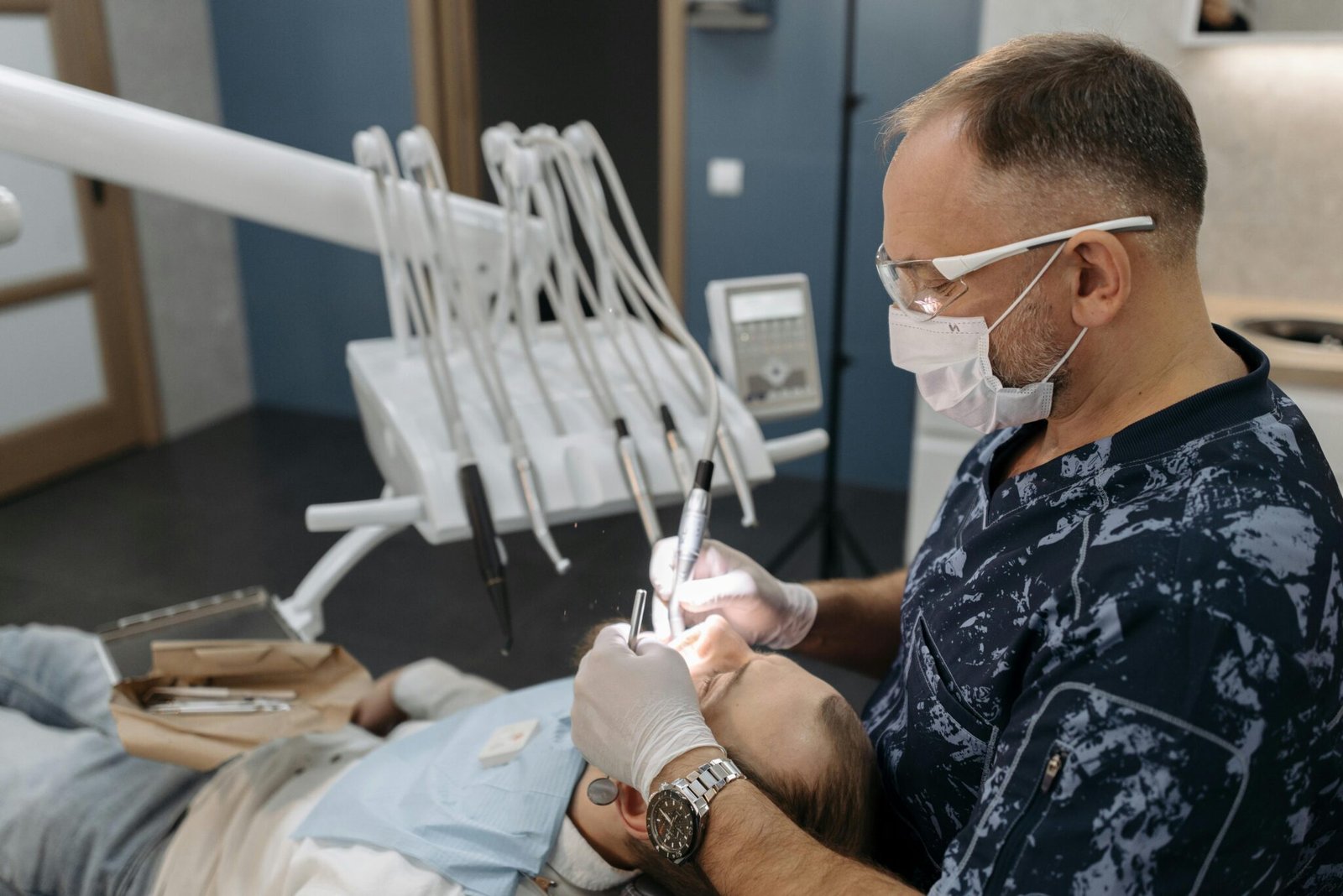 Dentist examining patient's teeth in a clinical setting with modern equipment.